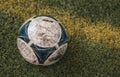 Selective closeup shot of a blue and white dirty soccer ball on grass
