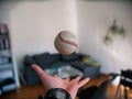 Selective closeup shot of a person tossing a gray baseball into the air