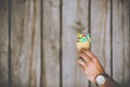 Selective closeup shot of a person wearing a ring and a wristwatch holding a multicolored ice cream