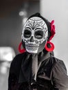 Selective color, black and red, portrait of woman wearing a sugar skull mask for dia de los muertos / day of the dead celebrated
