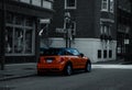 Selective color shot of an orange Mini Cooper car on the side of a street in Boston, USA