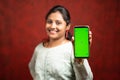 Selective focous on smartphone, Happy smiling Indian girl in traditional dress showing mobile phone with mock up green screen for Royalty Free Stock Photo