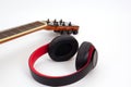 Selective focus, Acoustic guitar neck on a white background and the headphones are placed on the side. Royalty Free Stock Photo