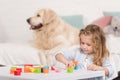 selective focus of adorable kid playing with educational cubes, golden retriever lying on bed