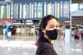 Selective focus at Adult Asian women wearing surgical face mask at Airport terminal in front of Arrival, Departure board. New Royalty Free Stock Photo