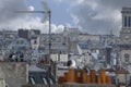 Selective focus aerial view of rooftops in Paris showing clay chimney pots, gothic tower, TV antenaes and people on a Royalty Free Stock Photo