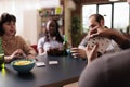 Selective focus of african american man holding cards while playing with best friends at home. Royalty Free Stock Photo