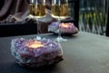 Selective focus on amethyst crystal geode candle holder with tea light candle burning inside.