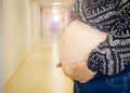 Selective focus on anonymous woman pregnant belly in birth clinic  out of focus hospital corridor on the background  regular medic Royalty Free Stock Photo