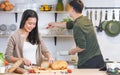 Selective focus Asian happy young adult woman cooking in cozy home kitchen in morning, preparing meal, making salad, bread for Royalty Free Stock Photo
