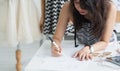Selective focus on Asian woman fashion designer or dressmaker hand, designing or drawing pattern and size of clothes, working Royalty Free Stock Photo