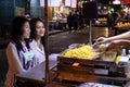 Selective focus asian young women friends sitting choose order corn butter dessert, enjoy eatting together in night market at