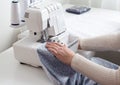in the atelier of a sewing workshop, a young girl sews a dress on an overlock. hands hold the fabric and stitch the