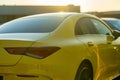 Selective focus back view of a bright yellow Mercedes-Benz car driving