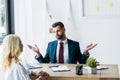 Focus of bearded recruiter showing shrug gesturing and looking at blonde employee