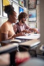 Selective focus on a beardy guy working together with his afro american young female colleague, sitting together at the office.