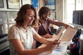 Selective focus on a beardy guy working together with his caucasian young female colleague, sitting together at the office