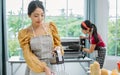 Selective focus on beautiful Asian woman using and preparing equipment to make bread in weekend in comfortable indoor kitchen at