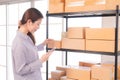 Selective focus Beautiful Asian working woman using smartphone to check goods on shelves for inventory management in warehouse. Royalty Free Stock Photo