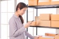 Selective focus Beautiful Asian working woman using smartphone to check goods on shelves for inventory management in warehouse. Royalty Free Stock Photo