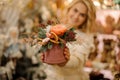 Selective focus of composition of rose and spruce branches and dried orange in round box in female hands