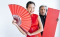 Selective focus beautiful happy Asian rich woman wearing red qipao or dress, smiling, holding folding fan with blur male bodyguard