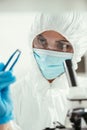 Focus of biochemist holding little stone with tweezers near microscope
