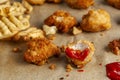 selective focus of bitten deep fried chicken nuggets dipped into red tomato ketchup on baking paper.