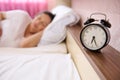 Focus on black alarm clock on blur pregnant woman, expectant mother sleeping, napping at daytime. Pregnancy. Home relax Royalty Free Stock Photo