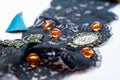 Black ornament lace with glass orange beads, green small frame, rhinestones, decorative butterfly and blue tassel Royalty Free Stock Photo