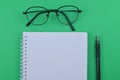 Selective focus of blank notebook , spectacles and pen on a green background. Business and education concept