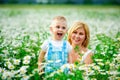 Selective focus. A blond son and mother in a field of daisies in bloom. Enjoy the fragrance of a bouquet of chamomile Royalty Free Stock Photo