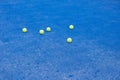 Selective focus. Blue paddle tennis court with synthetic grass and several yellow balls. Racket sports concept Royalty Free Stock Photo