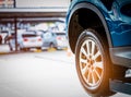 Selective focus on blue SUV car rear wheel on blurred background. Car with new high performance tire parked at garage workshop Royalty Free Stock Photo