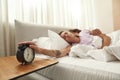 Woman stop alarm clock at morning near boyfriend Royalty Free Stock Photo