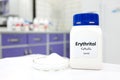 Selective focus of a bottle of pure erythritol sugar substitute artificial sweetener with powder in petri dish. White laboratory.