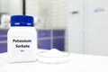 Selective focus of bottle of pure potassium sorbate food additive beside a petri dish with white solid powder