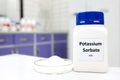 Selective focus of bottle of pure potassium sorbate food additive beside a petri dish with white solid powder