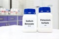 Selective focus of bottle of pure potassium sorbate and sodium benzoate food additive beside a petri dish with white solid powder