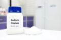 Selective focus of bottle of pure sodium oxalate toxic chemical beside a petri dish with white solid crystal powder substance.