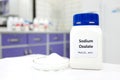 Selective focus of bottle of pure sodium oxalate toxic chemical beside a petri dish with white solid crystal powder substance.