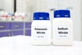 Selective focus of bottles of sodium nitrate and potassium nitrate chemical preservative. White laboratory background.