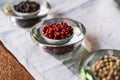 Selective focus on a bowl with red berries surrounded by other bowls with dry fruits on a cloth