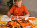 Selective focus a boy that carves a pumpkin out of orange paper for Halloween.