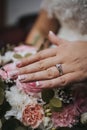 Selective focus of a bride's hands with a promise ring on the background of a bridal bouquet