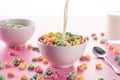 Selective focus of bright multicolored breakfast cereal in bowl with pouring milk near spoon Royalty Free Stock Photo