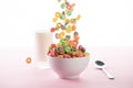 Selective focus of bright multicolored breakfast cereal falling in bowl near milk and spoon Royalty Free Stock Photo