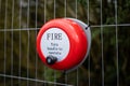 Bright red fire alarm bell turn handle spin around to operate alert manual steel ringing on construction building site