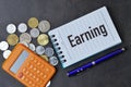 Selective focus of calculator, coins, pen and notebook written with text EARNING Royalty Free Stock Photo