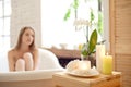 Selective focus of candles and flowers on the wooden table in spa salon with blurred woman on background. Royalty Free Stock Photo